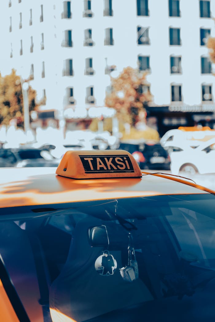 Close-up of a yellow taxi with 'Taksi' sign in a bustling urban environment.